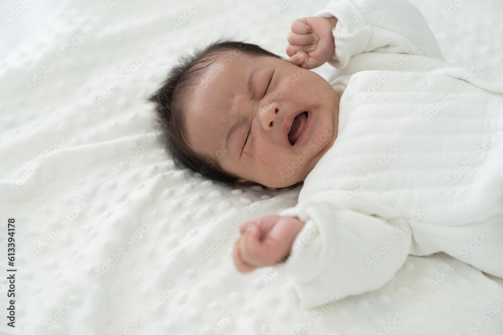 Newborn baby crying during sleeping on blanket on white bed. Asian newborn baby crying Newborn baby crying during sleeping on blanket on white bed. Asian newborn baby crying
