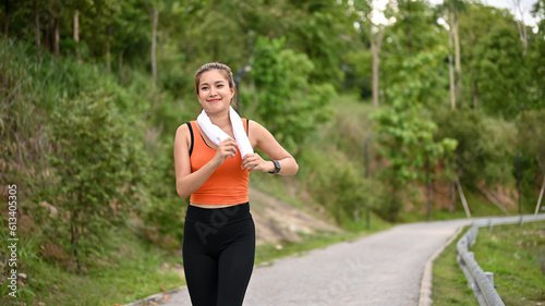 A sporty-fit Asian woman in sportswear enjoys running along the street in the park alone.