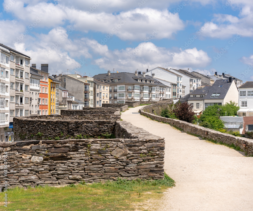 elevated walkway of a city wall from where you can see the top of the city houses and the cloudy sky