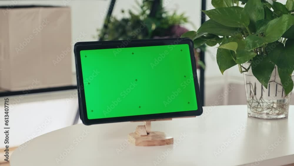 Close-up shot of digital tablet with green chroma key screen in wooden stand on table in living room, no people Close-up shot of digital tablet with green chroma key screen in wooden stand on table in living room, no people