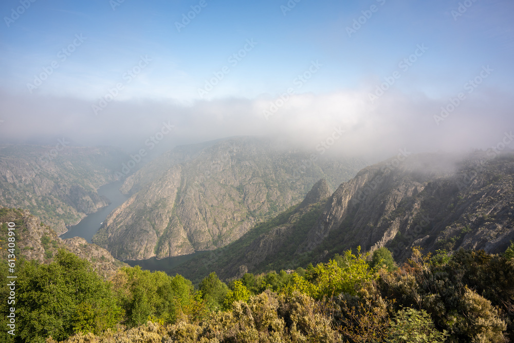 aerial view with a drone from the top of the canyon with the mountains on the sides of the river and thick fog above them