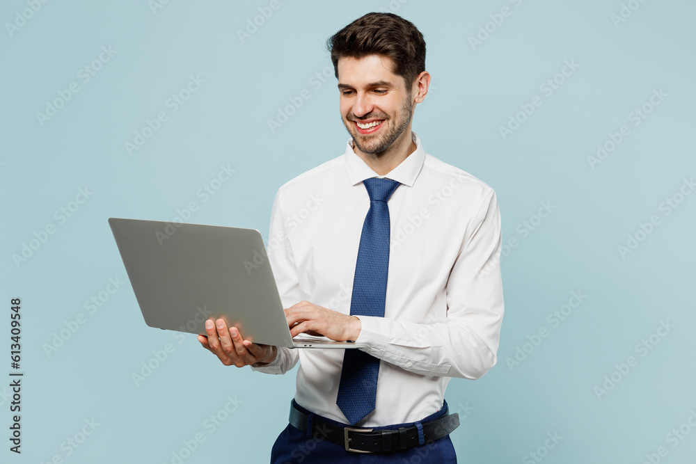 Young smiling employee IT business man corporate lawyer wear classic formal shirt tie work in office hold use work on laptop pc computer isolated on plain pastel light blue background studio portrait. Young smiling employee IT business man corporate lawyer wear classic formal shirt tie work in office hold use work on laptop pc computer isolated on plain pastel light blue background studio portrait.