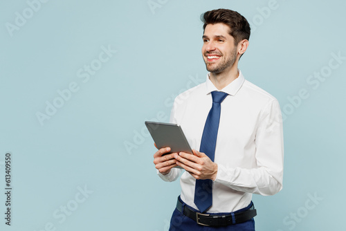 Young employee IT business man corporate lawyer wears classic formal shirt tie work in office hold use digital tablet pc computer look aside isolated on plain pastel blue background studio portrait.