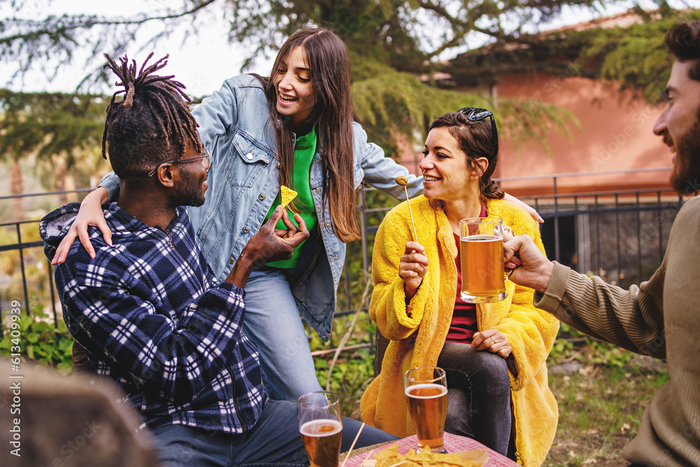 Multicultural Friends Embracing in an Outdoor Beer Garden. They enjoy beer, nachos, and olives.