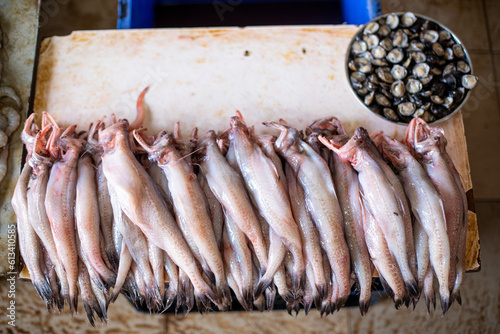 Fotografie Dried bombay duck lying on table next to plate of breezy molluscs