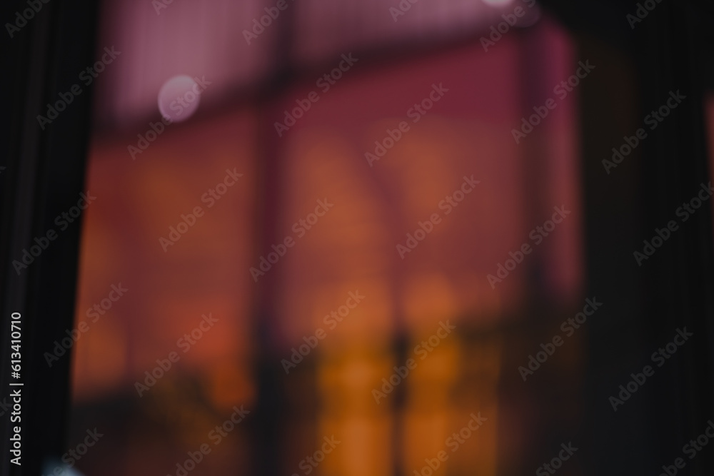 Fototapeta premium A defocused photo creates an abstract wallpaper out of orange and pink panels of glass combind with reflections and architectural details.