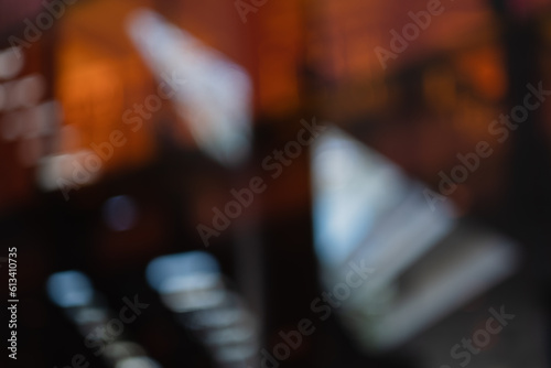 A defocused photo creates an abstract wallpaper out of orange and pink panels of glass combind with reflections and architectural details.