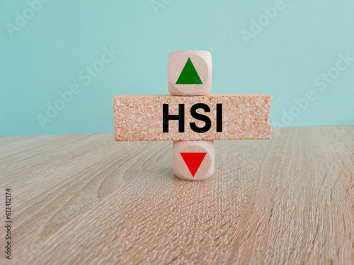 HSI price symbol. A brick block with arrow symbolizing that Hang seng index price are going down or up. Beautiful blue background. Business and gold price concept. Copy space. photo