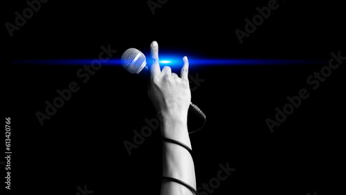 close up microphone in hand sign of singer raised his hand all the way up with blue light showing power, hope and love in live concert