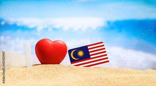 I love Malaysia. Flag of Malaysia on the beach with a red heart. vacation and travel concept.
