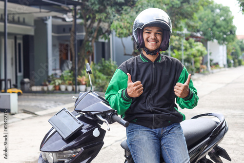 Asian man work as a commercial motorcyle taxi driver smiling while giving his thumb up photo