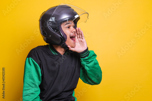 Asian online taxi driver motorbike man with shout gesture or making announcement over yellow background