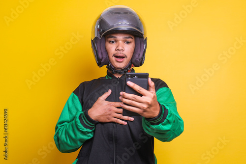 Asian online taxi driver motorbike man shocked and surprised while checking his smartphone isolated over yellow background
