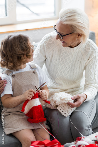 Grandmother and granddaughter spend quality time together, knitting, preparing handmade decoration for new year celebration. Cozy family festive home atmosphere, Christmas eve. Family traditions