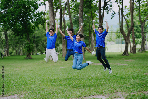 Volunteers of various nationalities are showing solidarity, donating their personal time, holding black trash bags to collect plastic waste for recycling to reduce pollution in a public park.