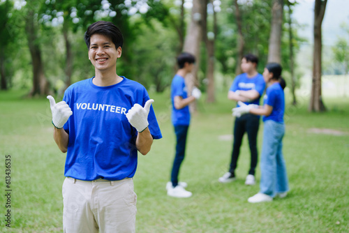 Multiethnic volunteers donate their time holding black garbage bags to collect plastic waste for recycling to reduce pollution in a public park.