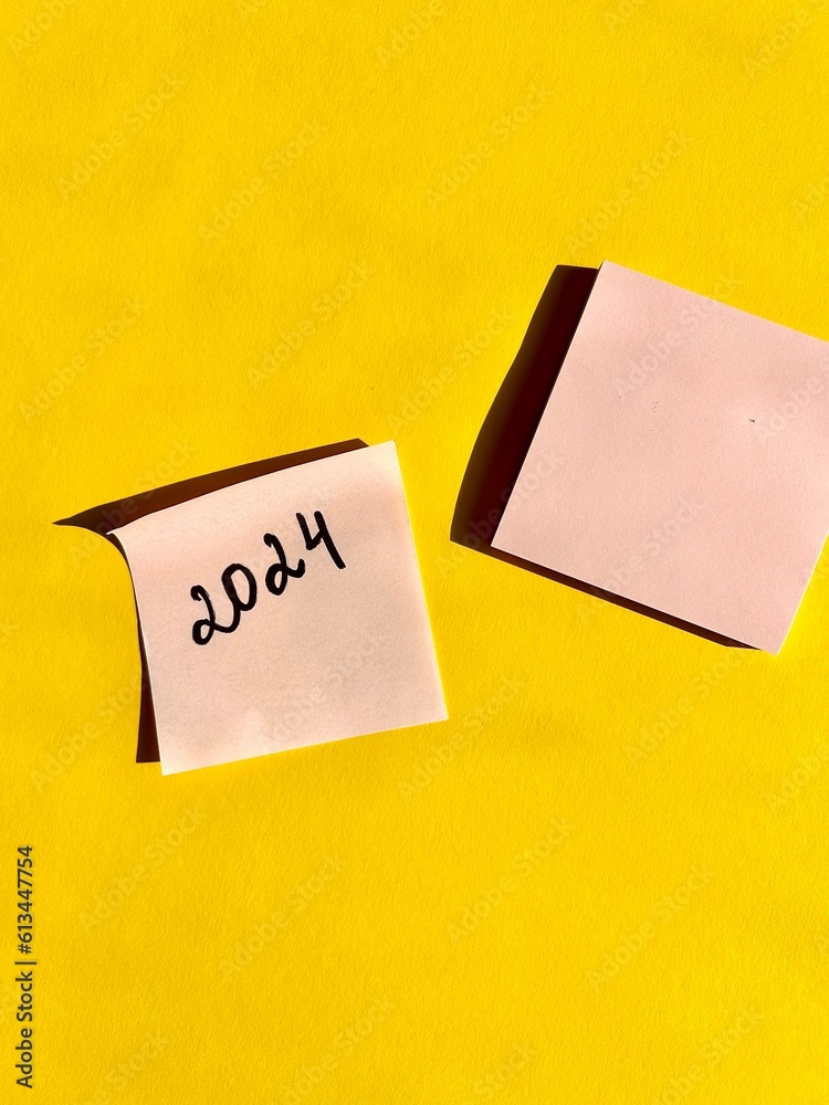 New Year 2024 written on note paper on a bright yellow background. Business concept. Plans for the new year. New Year 2024 written on note paper on a bright yellow background. Business concept. Plans for the new year.
