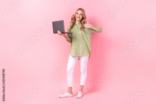 Full length photo of cute confident woman dressed green shirt thumb up working modern gadget isolated pink color background