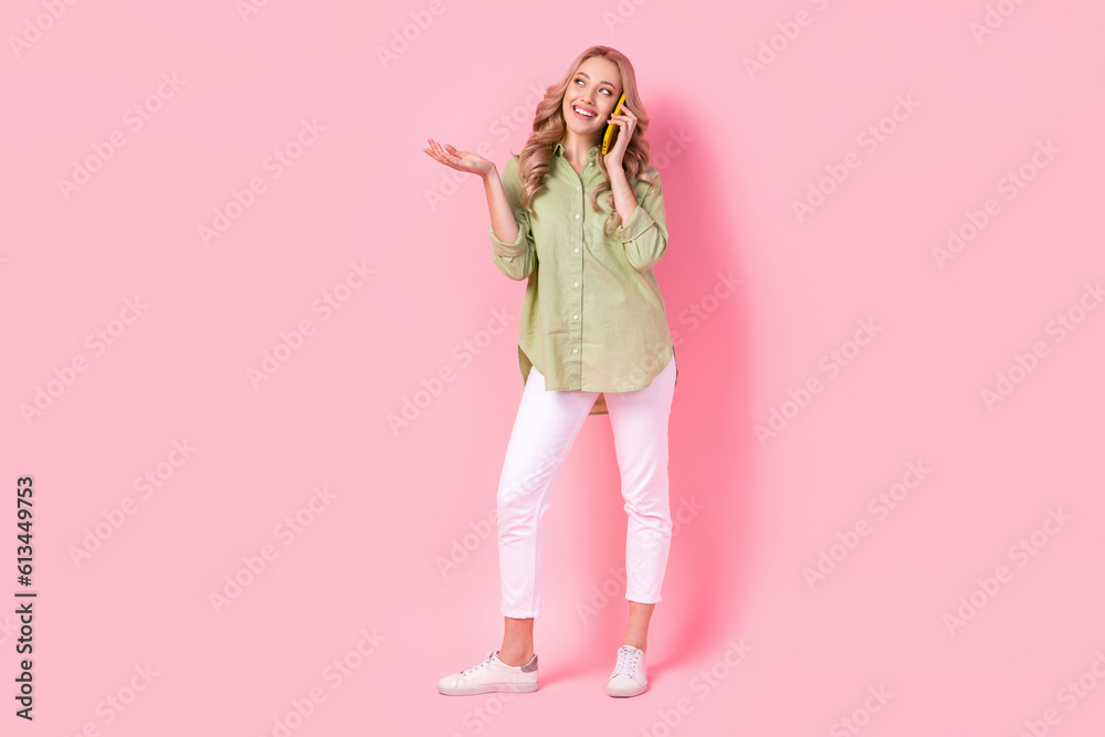 Full length photo of pretty dreamy woman dressed green shirt talking modern device looking empty space isolated pink color background Full length photo of pretty dreamy woman dressed green shirt talking modern device looking empty space isolated pink color background