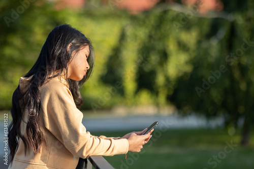 young girl walking in the park while talking and using her mobile phone