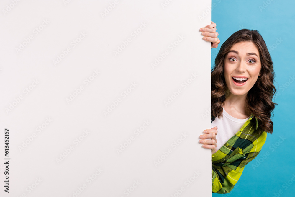 Photo of impressed pretty lady wear checkered jacket holding placard empty space isolated blue color background Photo of impressed pretty lady wear checkered jacket holding placard empty space isolated blue color background