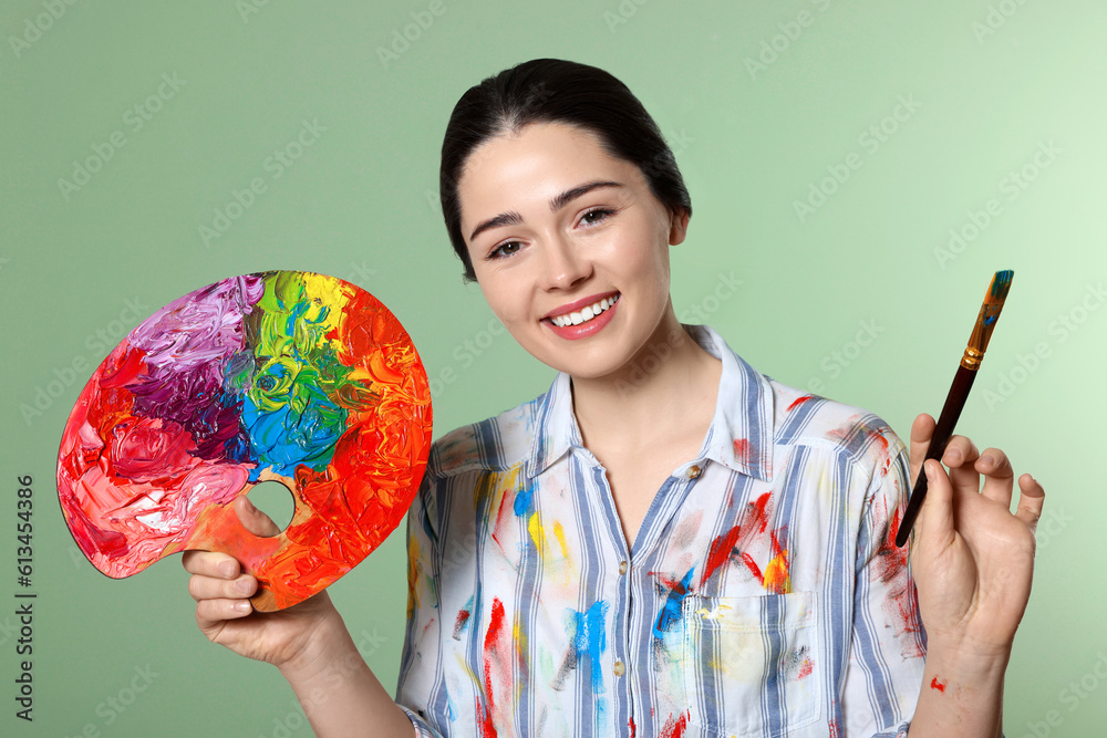 Fototapeta premium Woman with painting tools on pale green background. Young artist