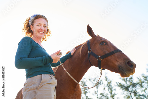 Low angle view of smiling female farmer with horse