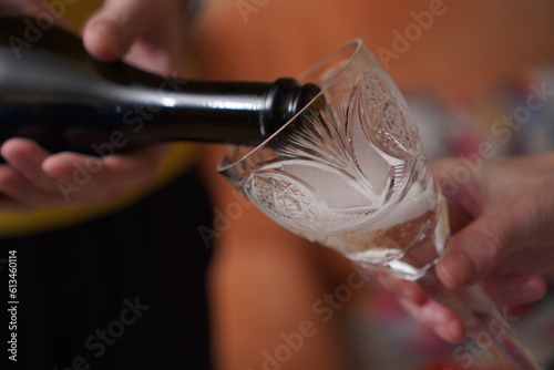a hand pours champagne from a bottle into a crystal glass close-up