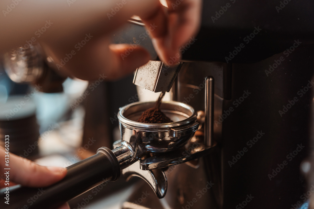 Coffee grinder grinds fresh coffee beans into a portafilter for espresso machine. Barista grind coffee bean with grinder machine. Selective focus. Coffee grinder grinds fresh coffee beans into a portafilter for espresso machine. Barista grind coffee bean with grinder machine. Selective focus.