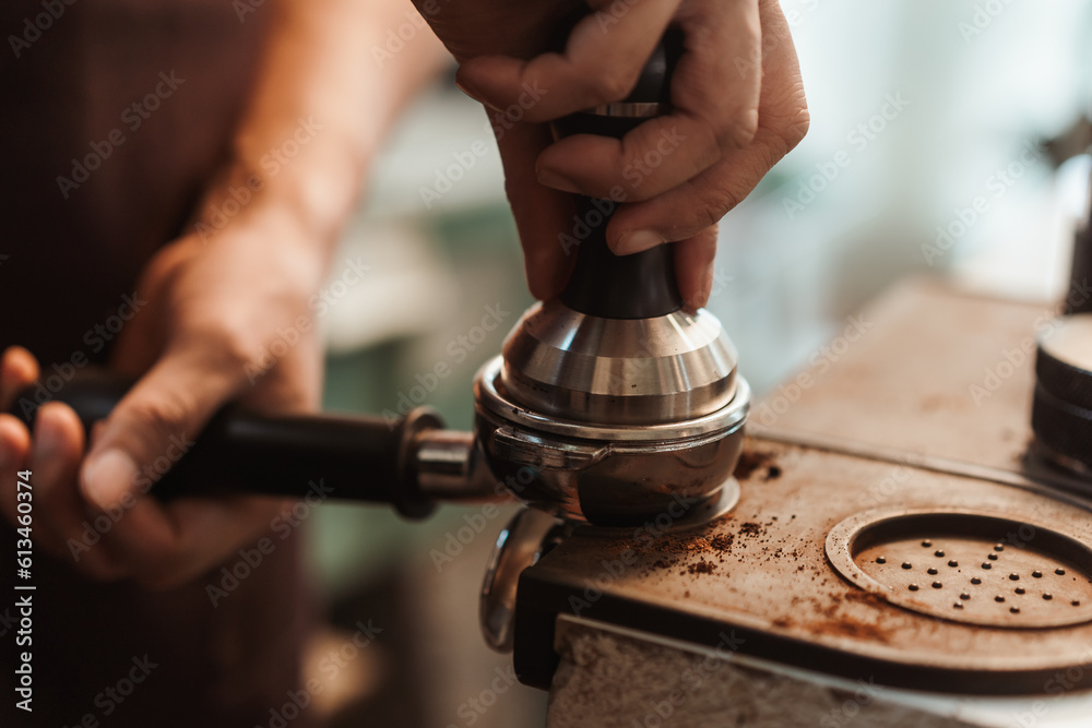 Closeup hand of barista preparation tampering ground coffee in