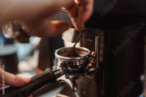 Coffee grinder grinds fresh coffee beans into a portafilter for  espresso machine. Barista grind coffee bean with grinder machine. Selective focus.