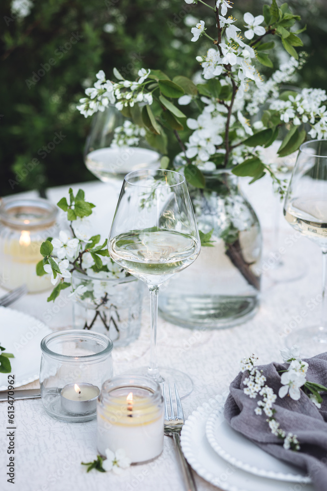 Rustic zero waste wedding decor with natural elements. Fresh spring blooming flowers, candles, linen napkins, wine glasses. Eco friendly decoration for the special holiday dinner. Romantic cozy place