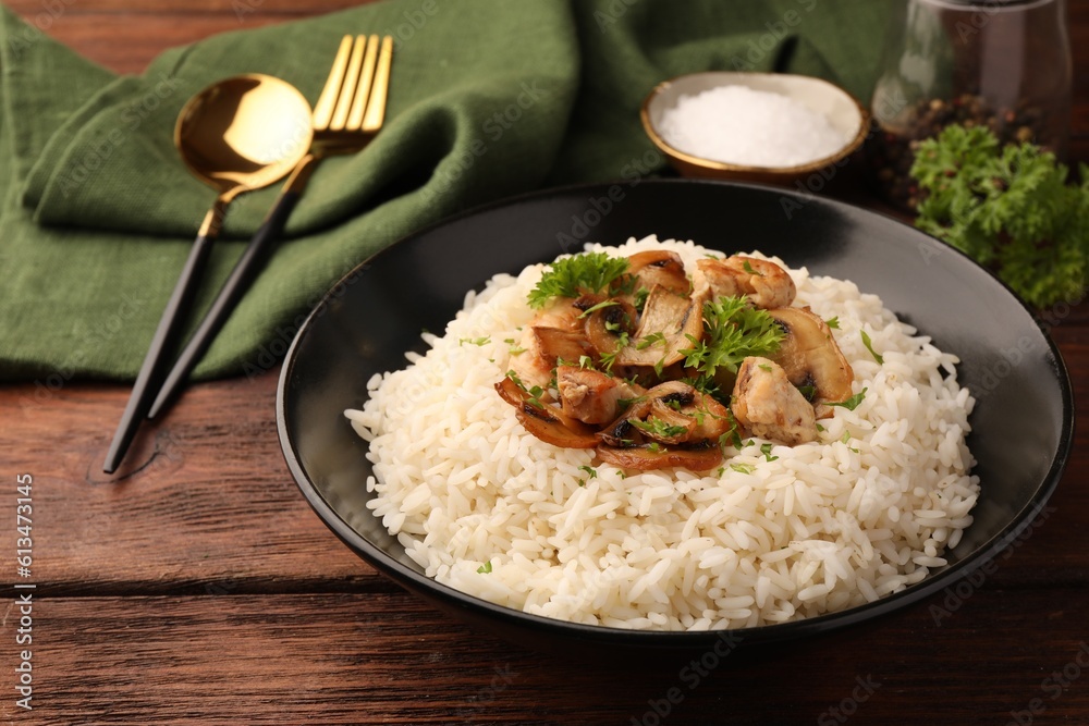 Delicious rice with mushrooms and parsley served on wooden table Delicious rice with mushrooms and parsley served on wooden table
