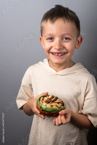 Boy holding a small bowl with brasil nuts. Healthy food and snack.