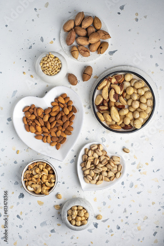 Different types of nuts on a plate in the shape of a heart. Assorted nuts on a white background. Top view.