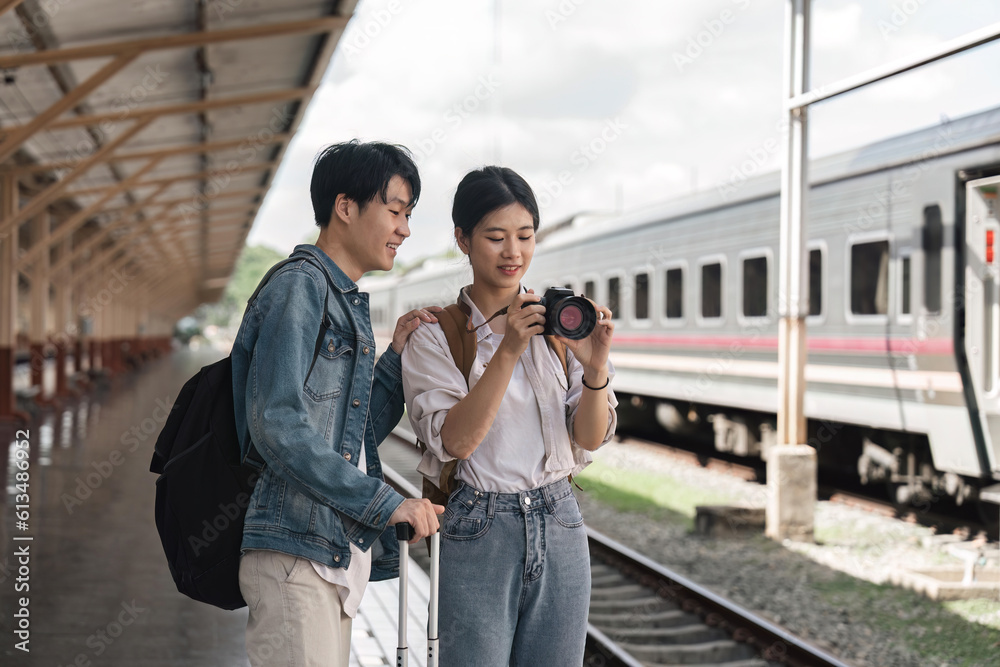 Beautiful couple at railway station waiting for the train. Young woman take pictures of trains. woman and man waiting to board a train