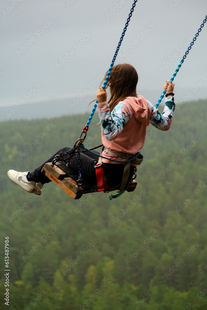 Girl rides on a swing background the forest