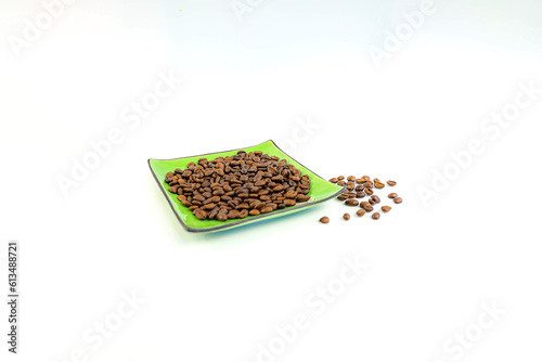 Coffee beans on a green square saucer, white background