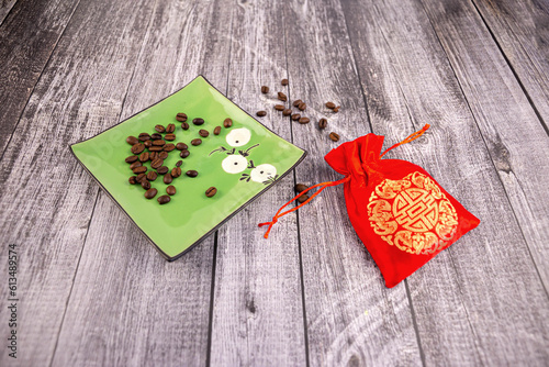 Coffee beans on a green saucer with a red pouch next to it, wooden background, photo at an angle