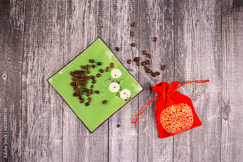 Coffee beans on a green saucer with a red bag next to it, wooden background, photo from above