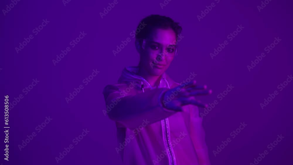 Woman in futuristic costume. Girl in glasses of virtual reality while touching air. Augmented reality game, future technology, AI concept. VR. Neon blue and red light. Dark background. Woman in futuristic costume. Girl in glasses of virtual reality while touching air. Augmented reality game, future technology, AI concept. VR. Neon blue and red light. Dark background.