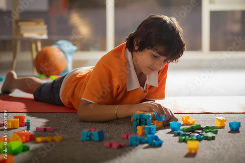 Boy playing with toy blocks while lying on floor