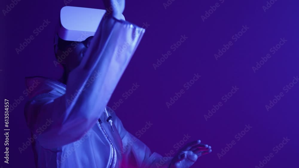 Woman in futuristic costume. Girl in glasses of virtual reality while touching air. Augmented reality game, future technology, AI concept. VR. Neon blue and red light. Dark background. Woman in futuristic costume. Girl in glasses of virtual reality while touching air. Augmented reality game, future technology, AI concept. VR. Neon blue and red light. Dark background.