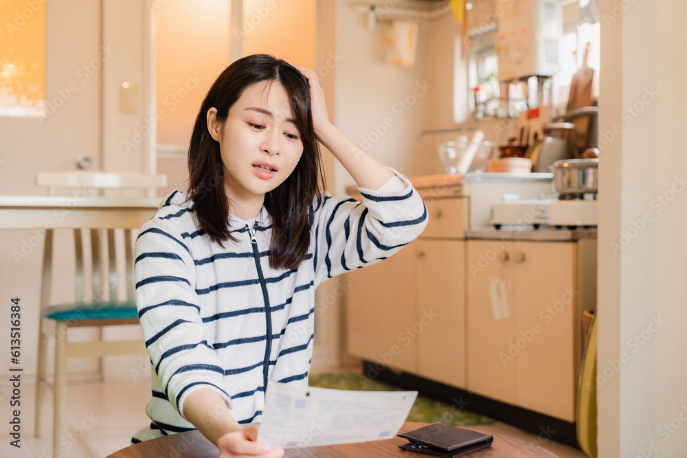電気料金の高騰で頭を抱える若い女性 電気料金の高騰で頭を抱える若い女性