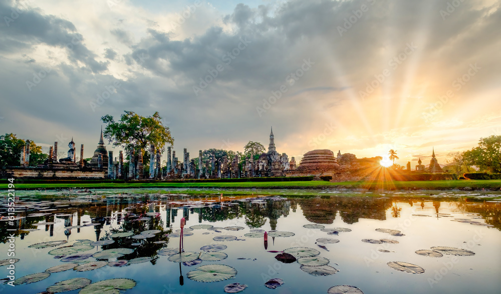 Sunset over Wat Mahathat Buddhist temple in Sukhothai historical park with dramatic sky and clouds.