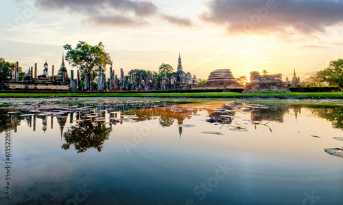 Sunset over Wat Mahathat Buddhist temple in Sukhothai historical park with dramatic sky and clouds. © Amonsak