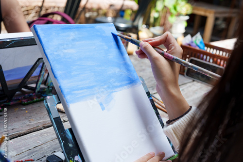 Close-up painter woman's hand holding long-handled paintbrush soft brush bristles, is using paintbrush paint on piece cloth, deep blue is color sea, that intends tell story with pictures. photo