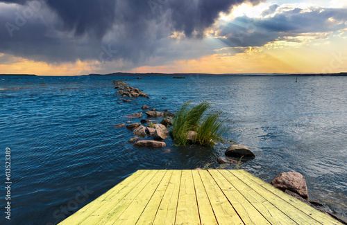 Sunset over the sea and old broken fishing pier on foreground