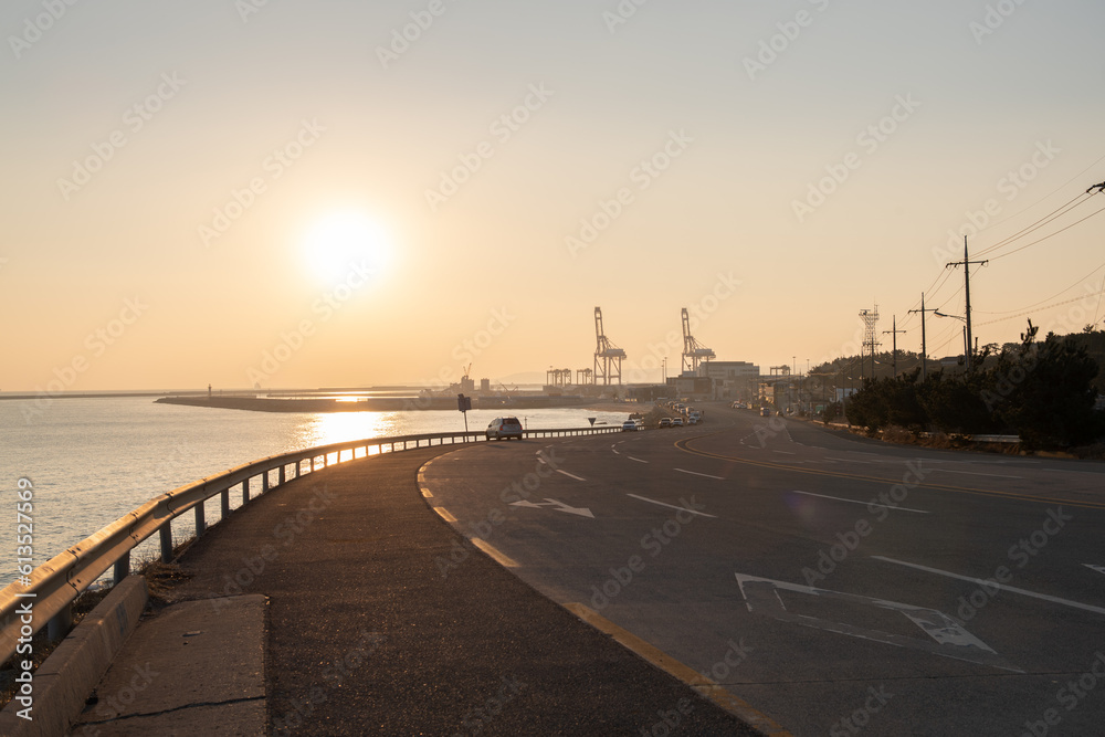 Sunrise on the coastal road with container cranes visible
