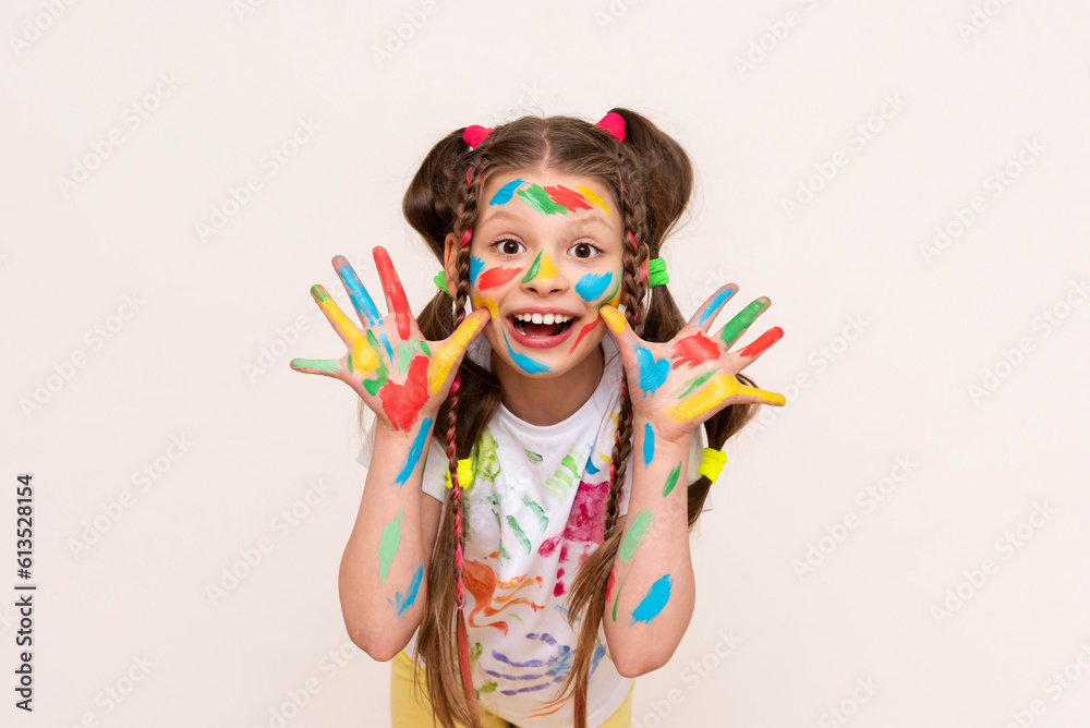 A little girl shows her palms painted with multicolored paints and smiles. A schoolgirl artist draws with her own hands. Creative education of children. White isolated background.